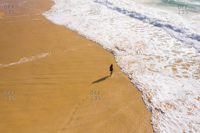 Aerial view of woman walking alone at hidden beach at Alexandria Bay, Australia.