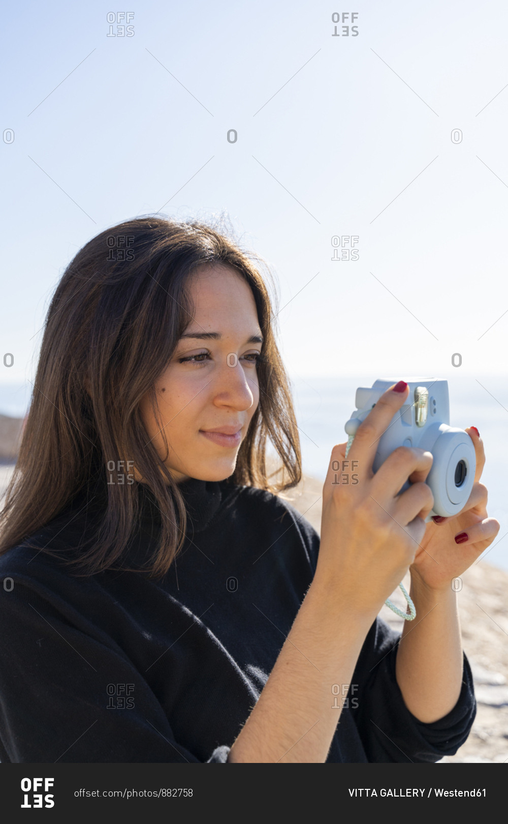 Portrait of young brunette woman photographing with blue camera stock ...