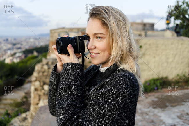 Young woman taking pictures above the city at sunrise- Barcelona- Spain