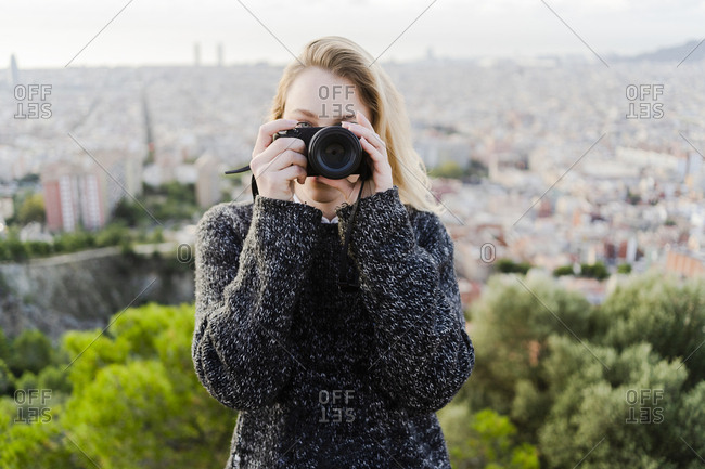 Young woman taking pictures above the city at sunrise- Barcelona- Spain
