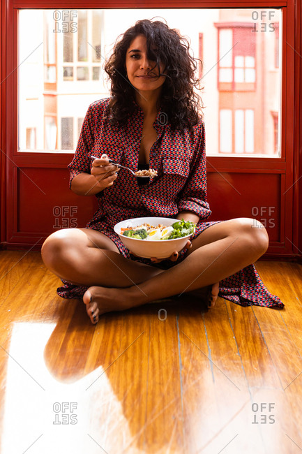 Latin woman eating a healthy while lunch sitting on the floor