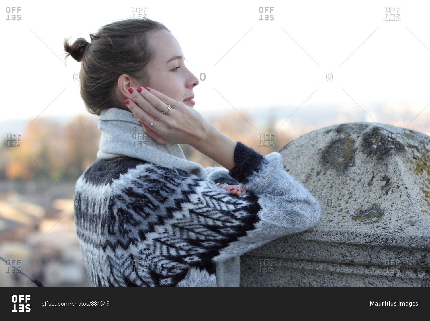A young woman leaning at a stone wall in Toledo,