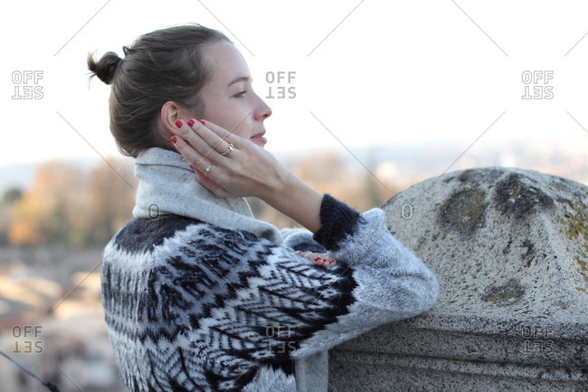 A young woman leaning at a stone wall in Toledo,