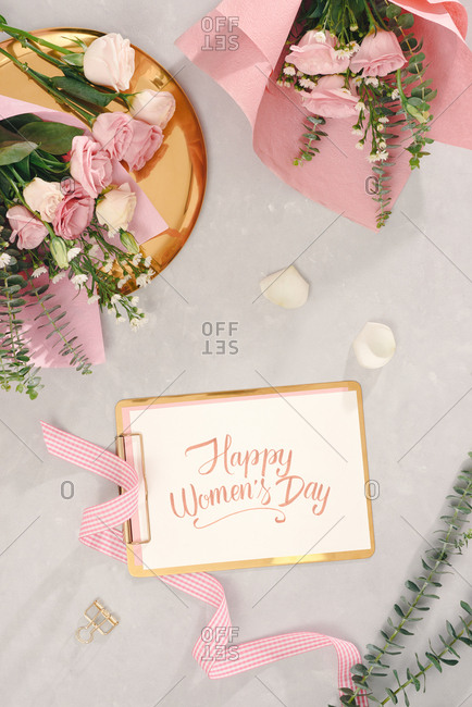 Happy women's day with hand writing script, flower bouquets on light background. top view, flatlay.