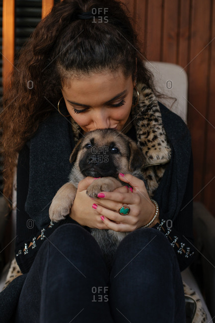 Portrait of a brunette girl kissing and snuggling a puppy