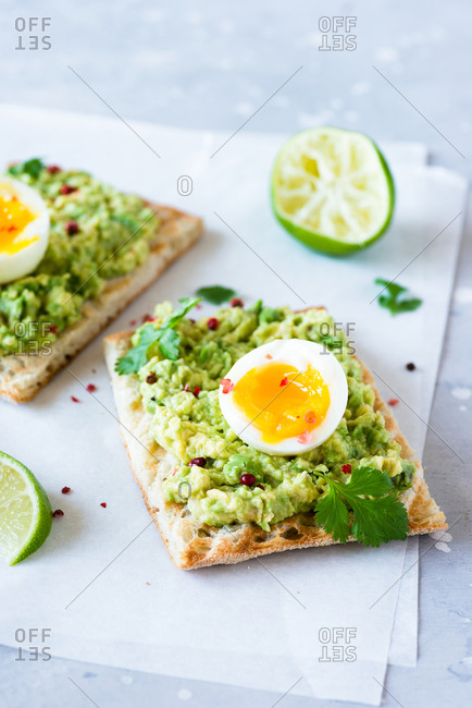 Close up of avocado toast with soft-boiled eggs and lime