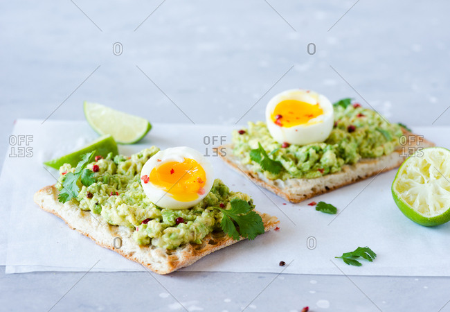 Avocado toast with soft-boiled eggs and lime over blue backdrop