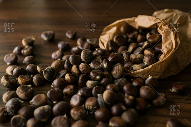 Bag filled with chestnuts spilled on wooden table
