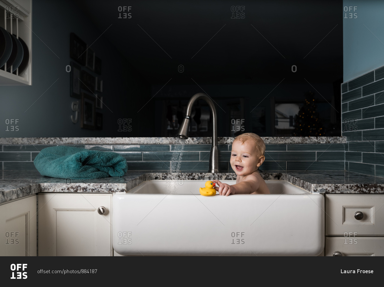 Baby taking bath in kitchen sink with rubber duck