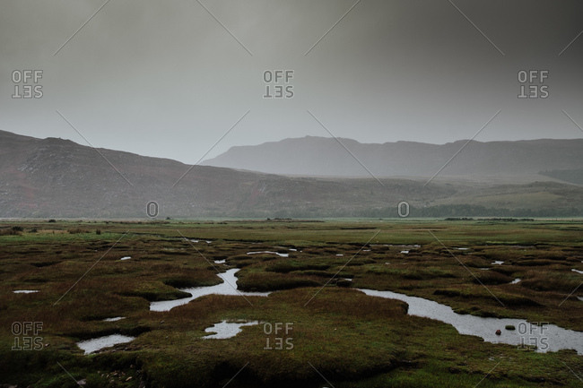 Autumn valley covered with water patches after rain surrounded by foggy hills in Scotland