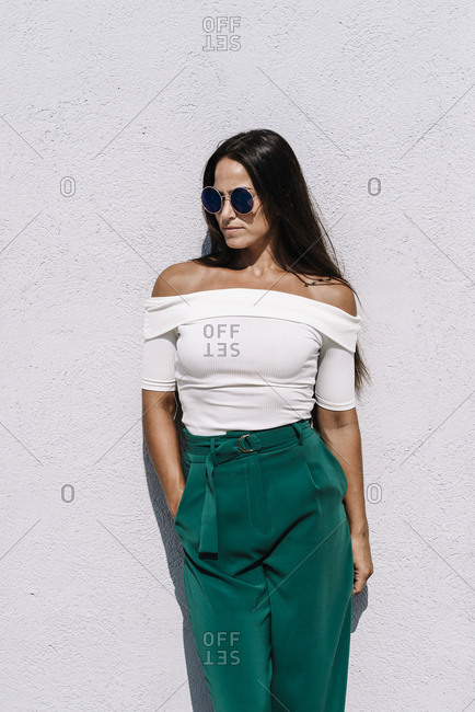 Elegant young woman leaning against a wall looking away