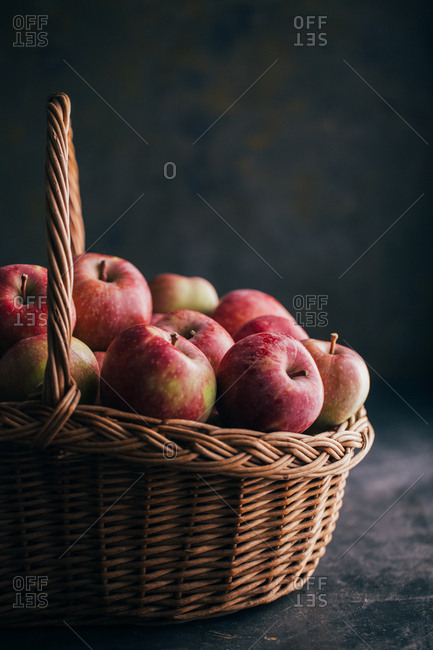 Fresh red apples on dark table and in a wicker basket on dark background
