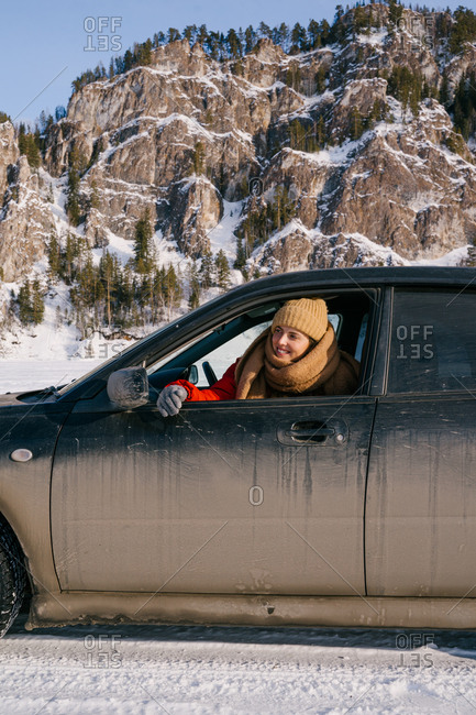 Woman leaning out car window on snowy valley