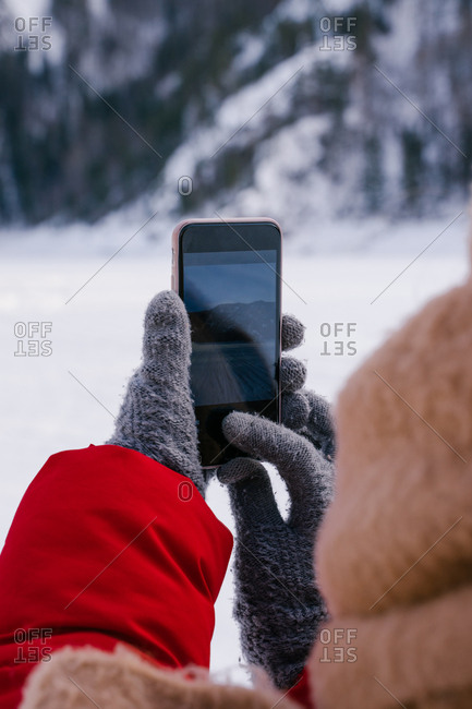 Woman taking picture of snowy mountains with smartphone