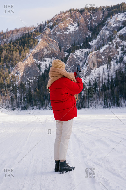 Woman taking picture of snowy mountains with smartphone