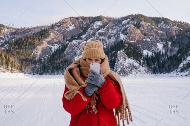 Woman taking picture of snowy mountains with smartphone