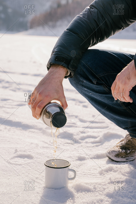Man pouring tea from thermos bottle on winter day