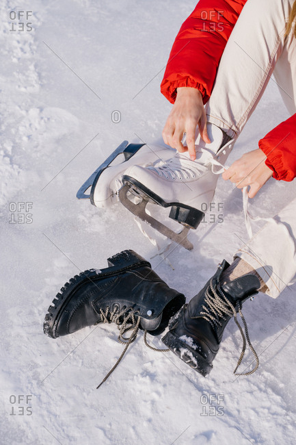 Woman sitting on snow and changing boots