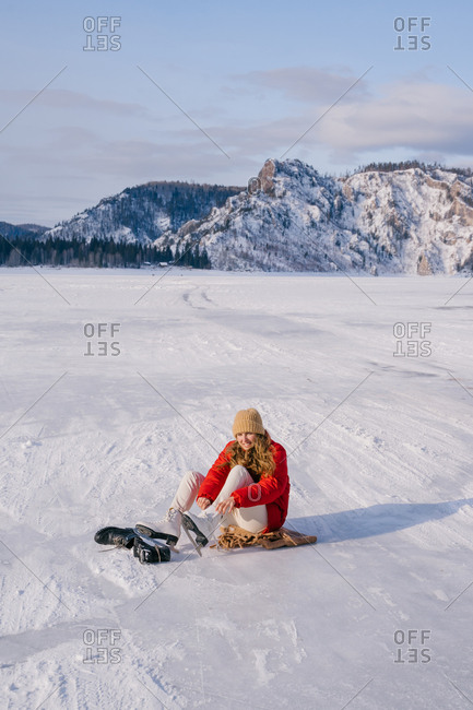 Woman sitting on snow and changing boots