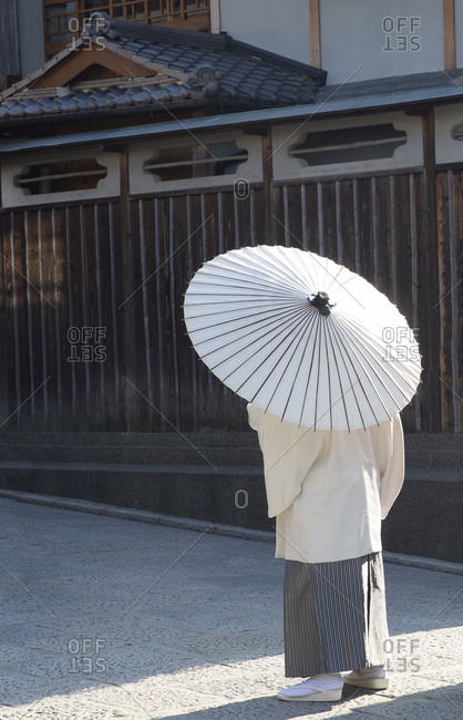 Man dressed in traditional clothing and walking with parasol in Old Town, Kyoto, Japan