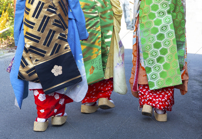 Maiko studying Geisha returning from shopping trip in Kyoto market, wearing wooden shoes, Kyoto, Japan