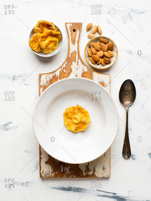 Slice of dried pineapple in a bowl and almond nuts