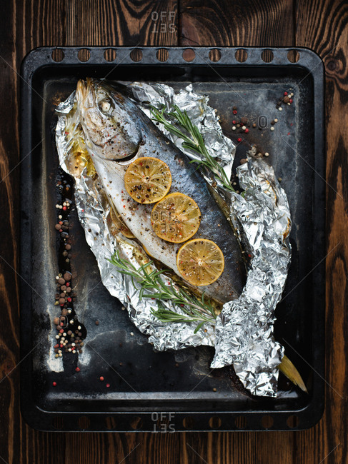 Overhead view of whole tuna fish baked with herbs, lemons, pepper and salt