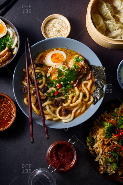 Asian cuisine dishes: pork ramen with soy-marinated eggs, vegetarian fried rice and gyoza dumplings served in a bamboo steamer