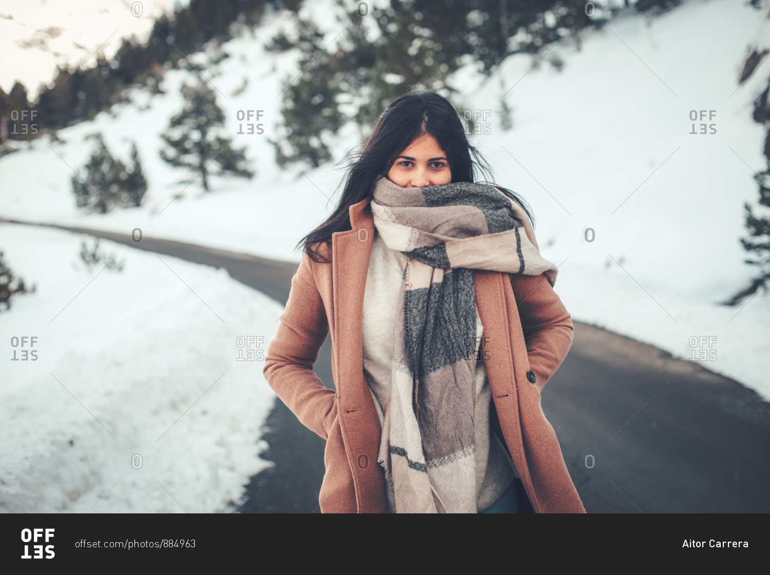 Young woman with dark hair bundled in thick scarf on rural road in winter