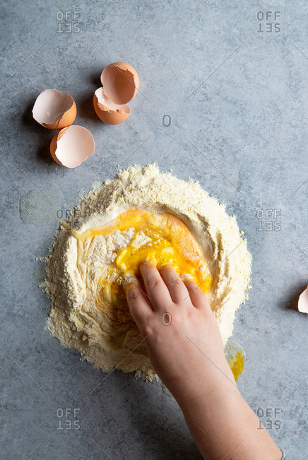Woman making fresh pasta with Semolina flour and eggs from above