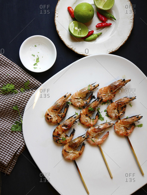 Overhead view of roasted shrimps in skewers on plate