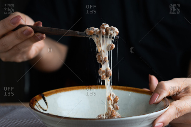 Cropped hand of woman pick a natto� from bowl by chopsticks