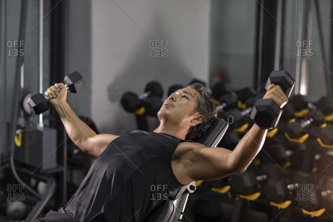 Mature Chinese man working out with hand weights at gym