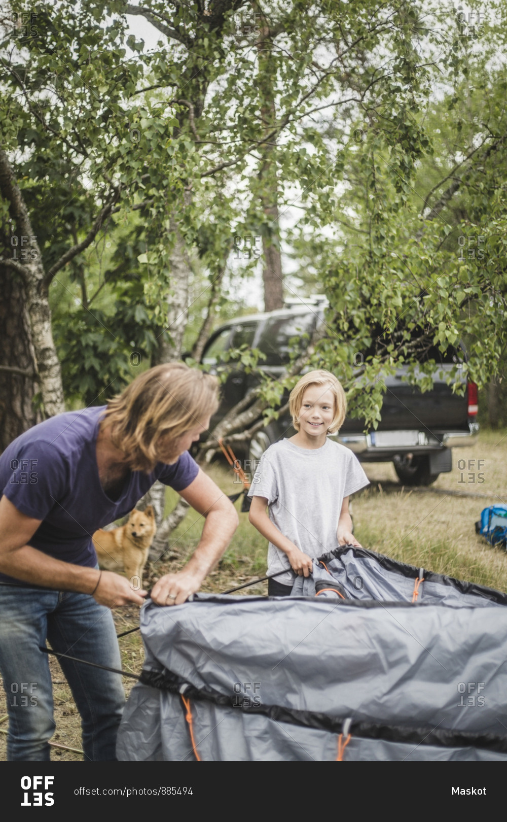 Father and daughter talking while pitching tent at camping site