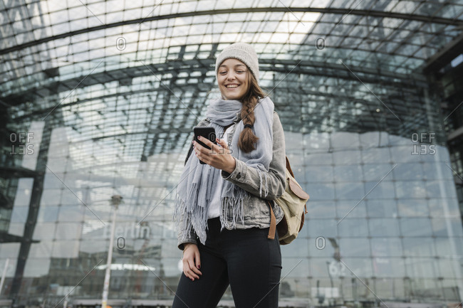Happy young woman using smartphone at the central station- Berlin- Germany