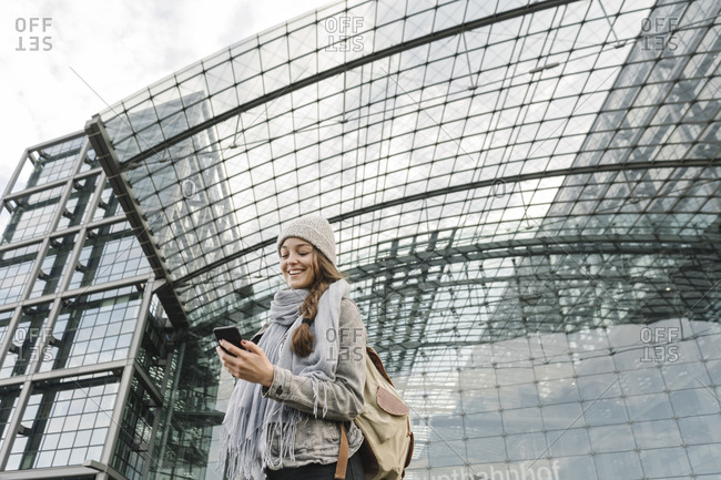 Happy young woman using smartphone at the central station- Berlin- Germany