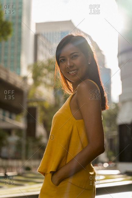 Portrait of fashionable woman dressed in yellow standing at backlight
