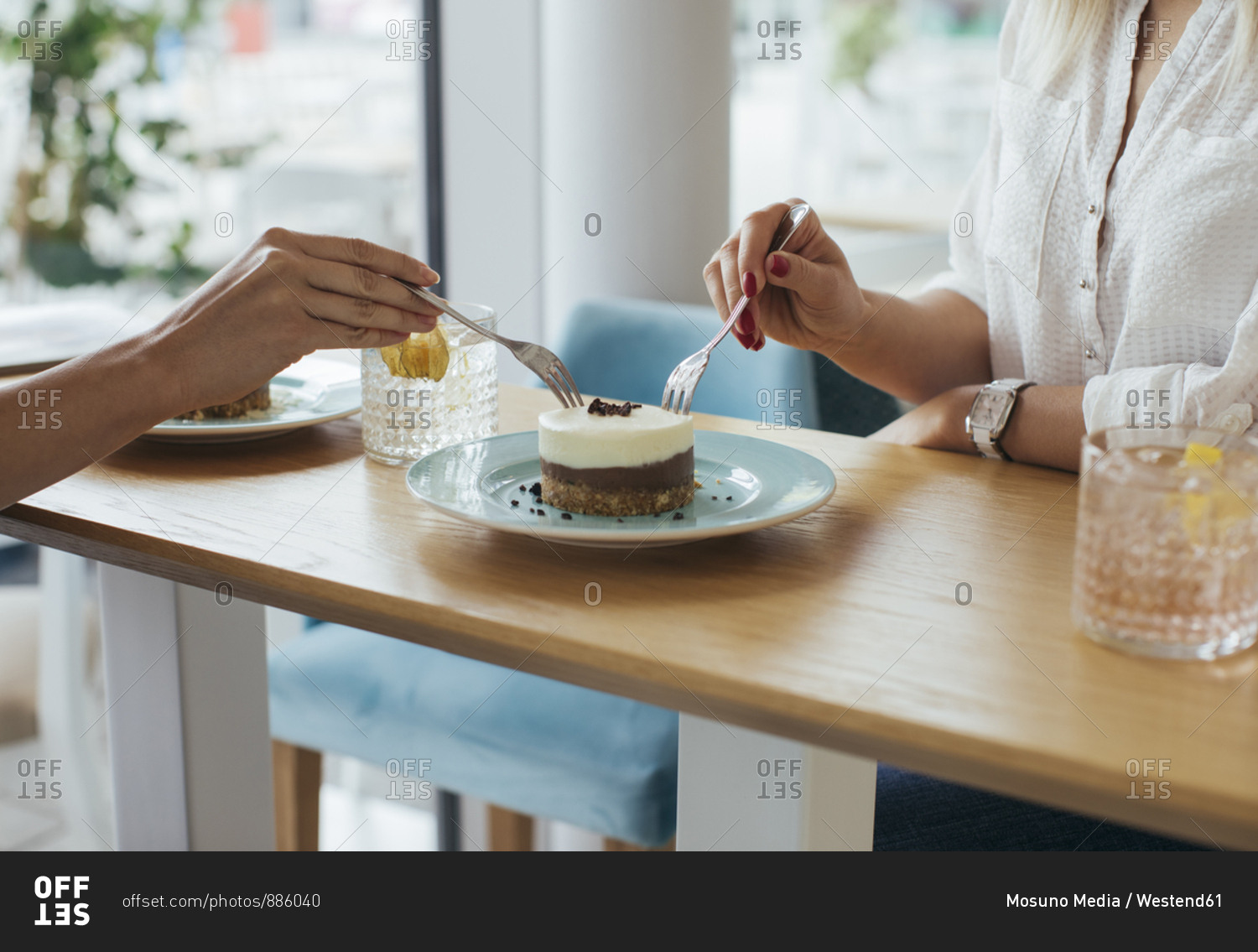 Anonymous young women sharing a cake at coffee shop