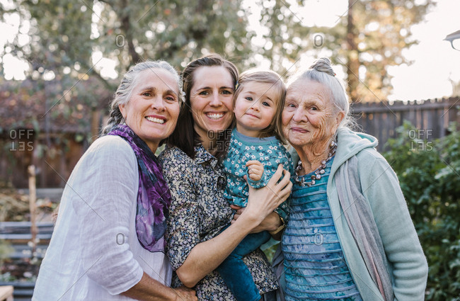 Portrait of four generations of women in a garden, smiling at the camera