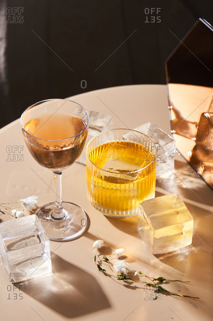 Cocktails beside cube shaped ice cubes and mirror