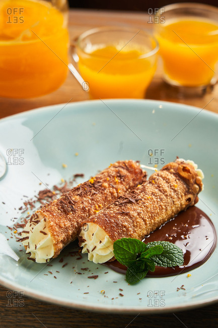 Orange juice beside dish with delicious cannolis