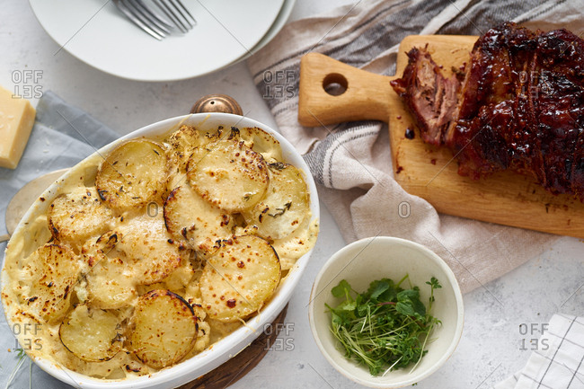 Overhead image of dinner with roasted pork and gratin dauphinoise with watercress