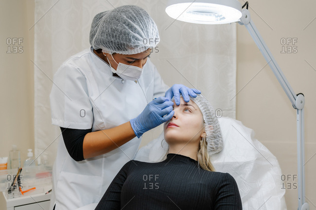 Beautician prepares the patient before applying a corrector treatment of eyebrows