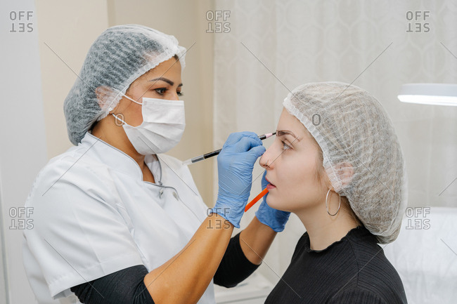 Esthetician performs a corrector treatment of eyebrows on a young woman