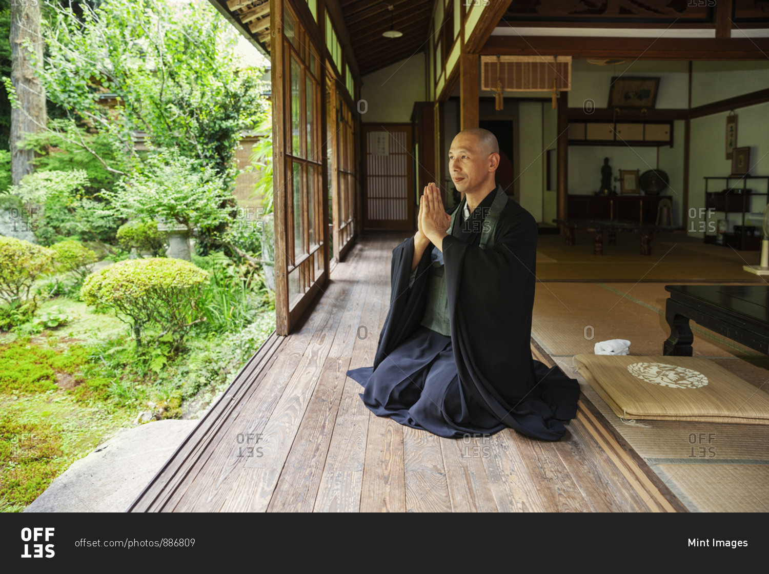 Buddhist priest kneeling in Buddhist temple, praying. stock photo - OFFSET