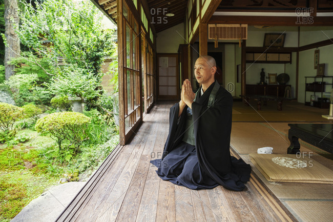 Buddhist priest kneeling in Buddhist temple, praying.