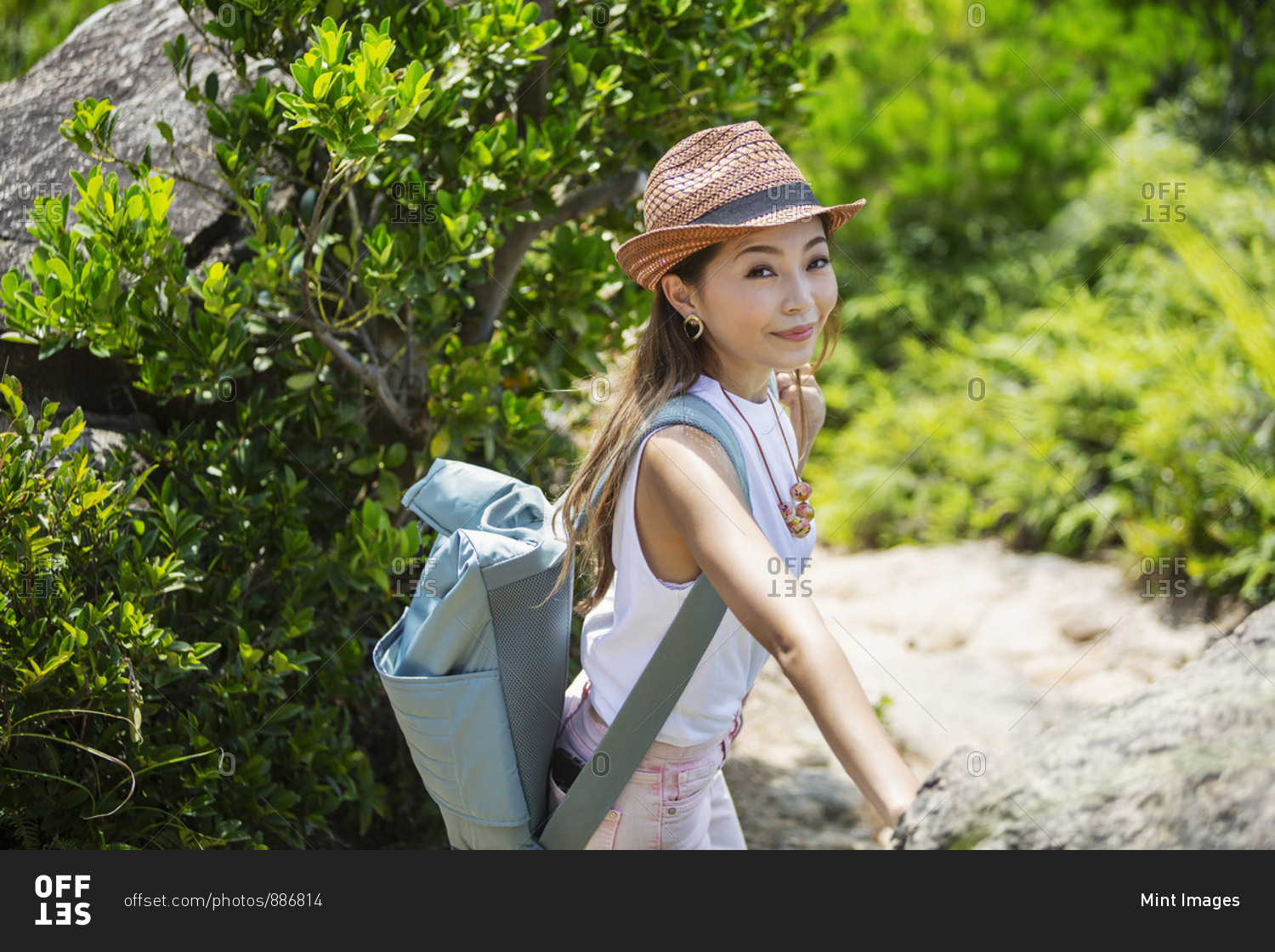 Japanese woman wearing hat and carrying backpack on a hike.