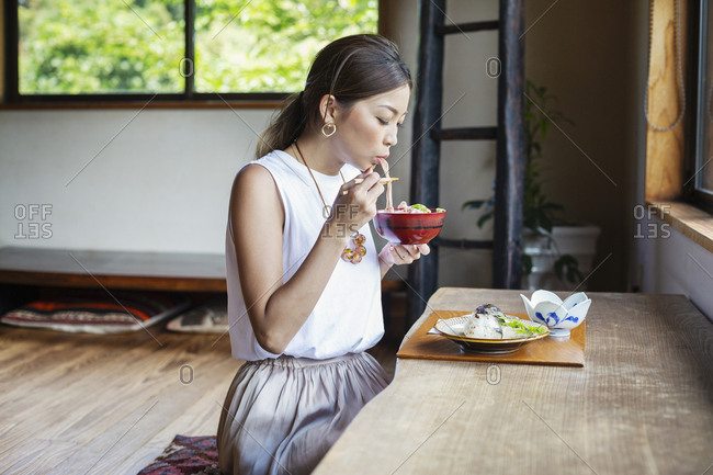 Japanese woman sitting at a table in a Japanese restaurant, eating.