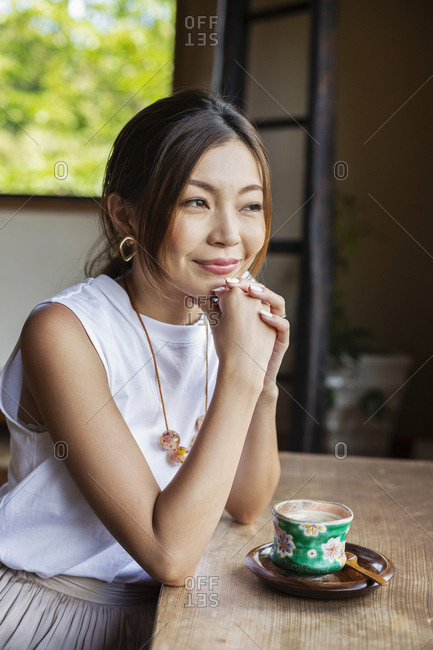 Smiling Japanese woman sitting at table in Japanese restaurant.