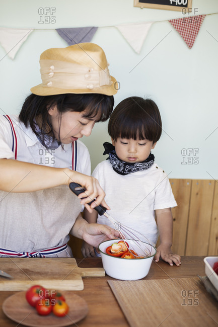 Japanese woman and boy standing in a farm shop, preparing food.